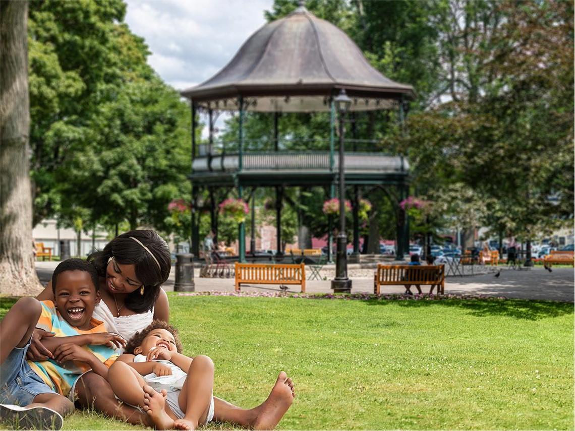 Family of three sitting on grass at Kings Square park Saint John