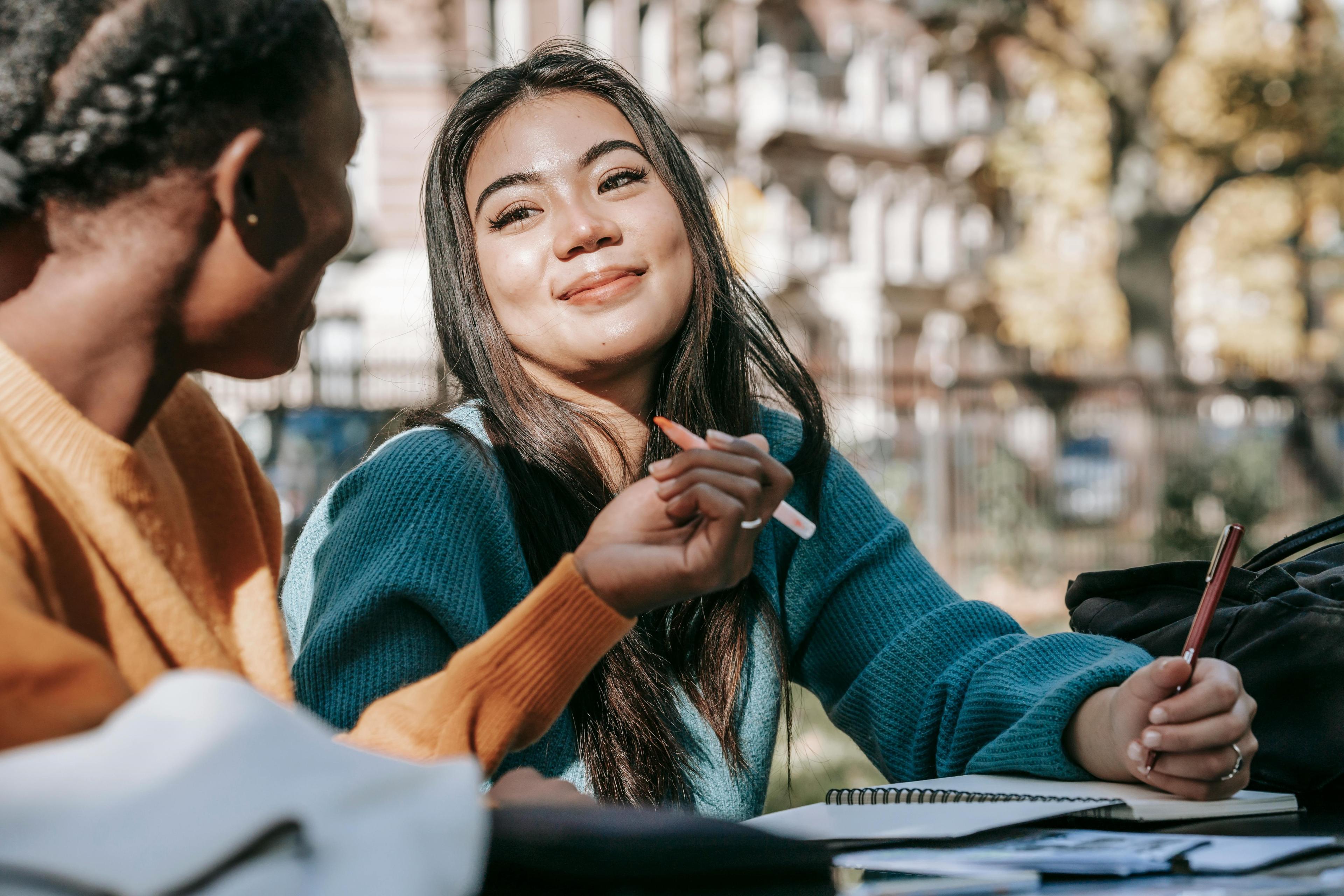 Two students sitting outside with a notepad and pencil