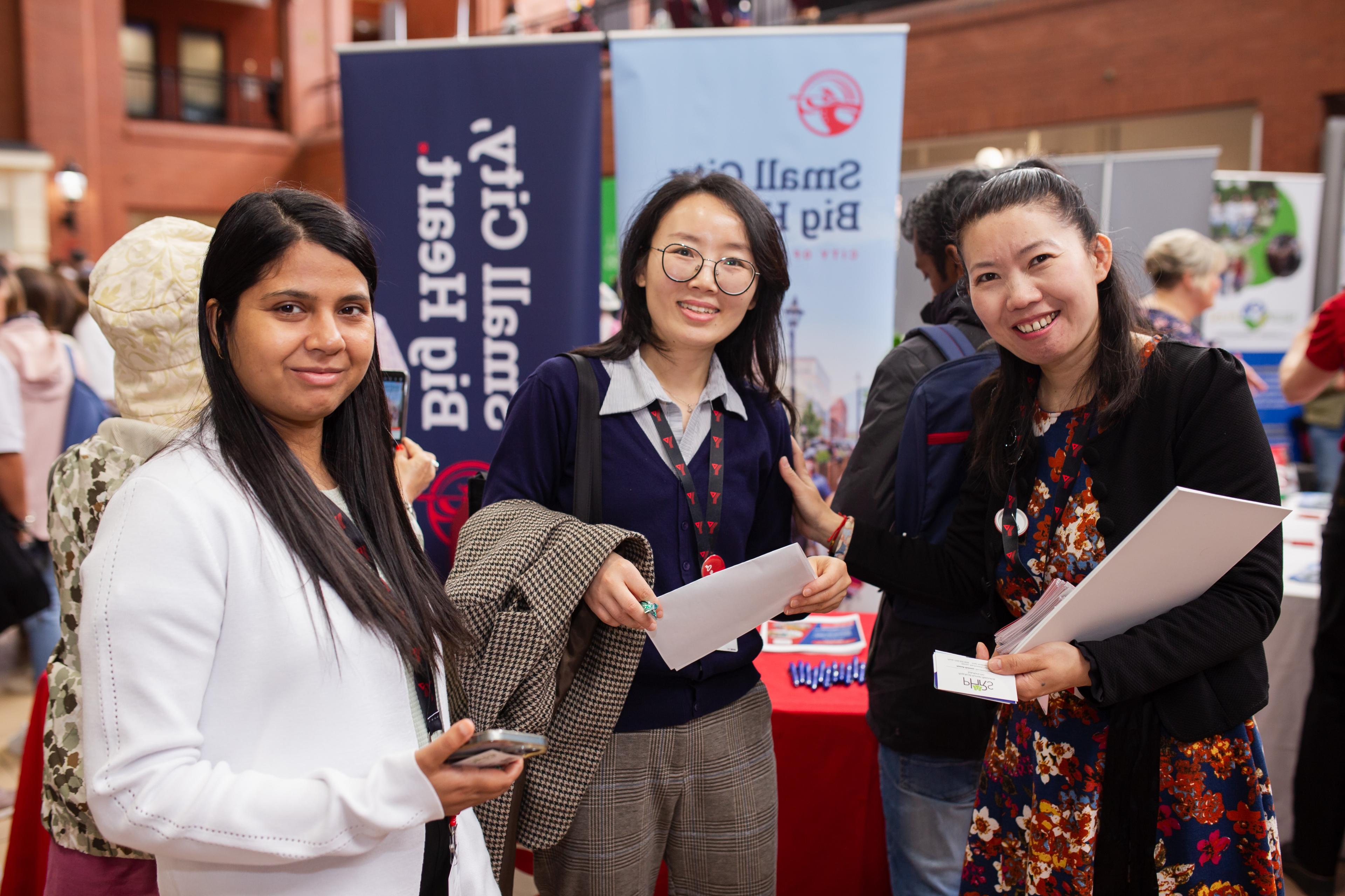 Three people standing together smiling at a career fair