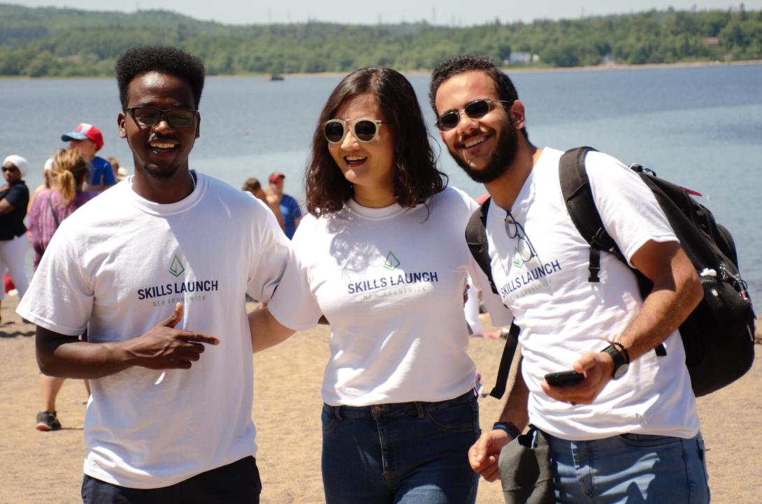 Three people smiling on a beach