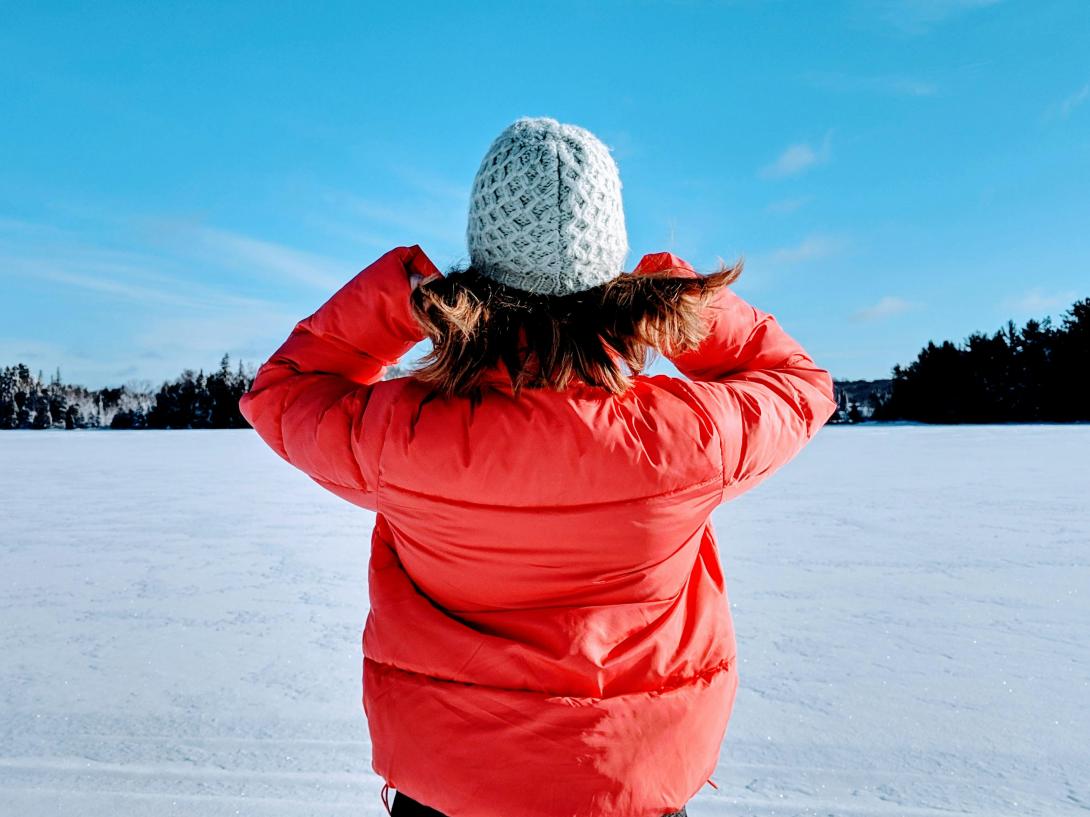 Person standing with winter coat and hat on snow