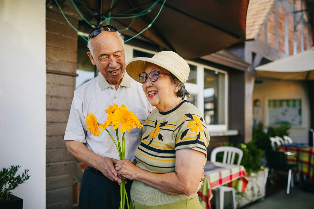 Two people standing together holding bouquet of flowers