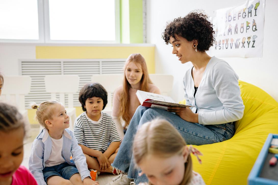 Children with teacher at school reading a book